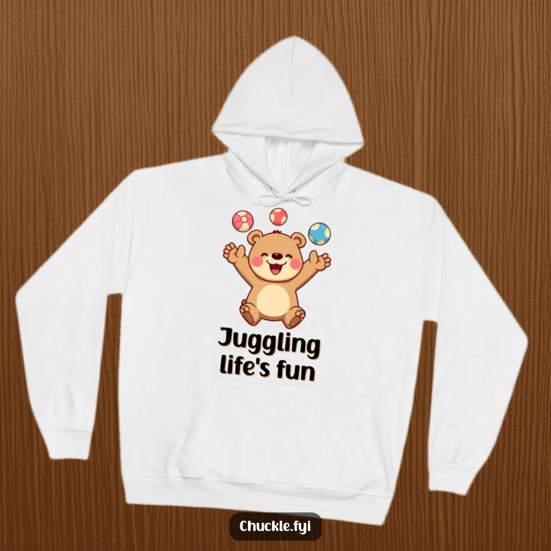 Funny hoodie depicting a cheerful bear character juggling three colorful balls, its wide smile radiating happiness. Cozy and talented.